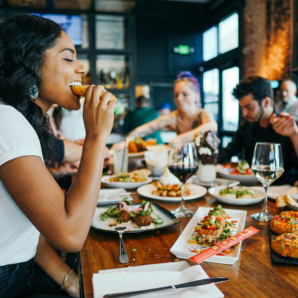 Group of friends enjoying diverse dishes at a restaurant in Singapore, featuring shared plates, wine, and dessert during a casual dining experience.