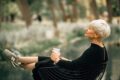 Confident older woman in black dress relaxing outdoors with a coffee, embodying grace, self-assurance, and healthy aging during menopause.