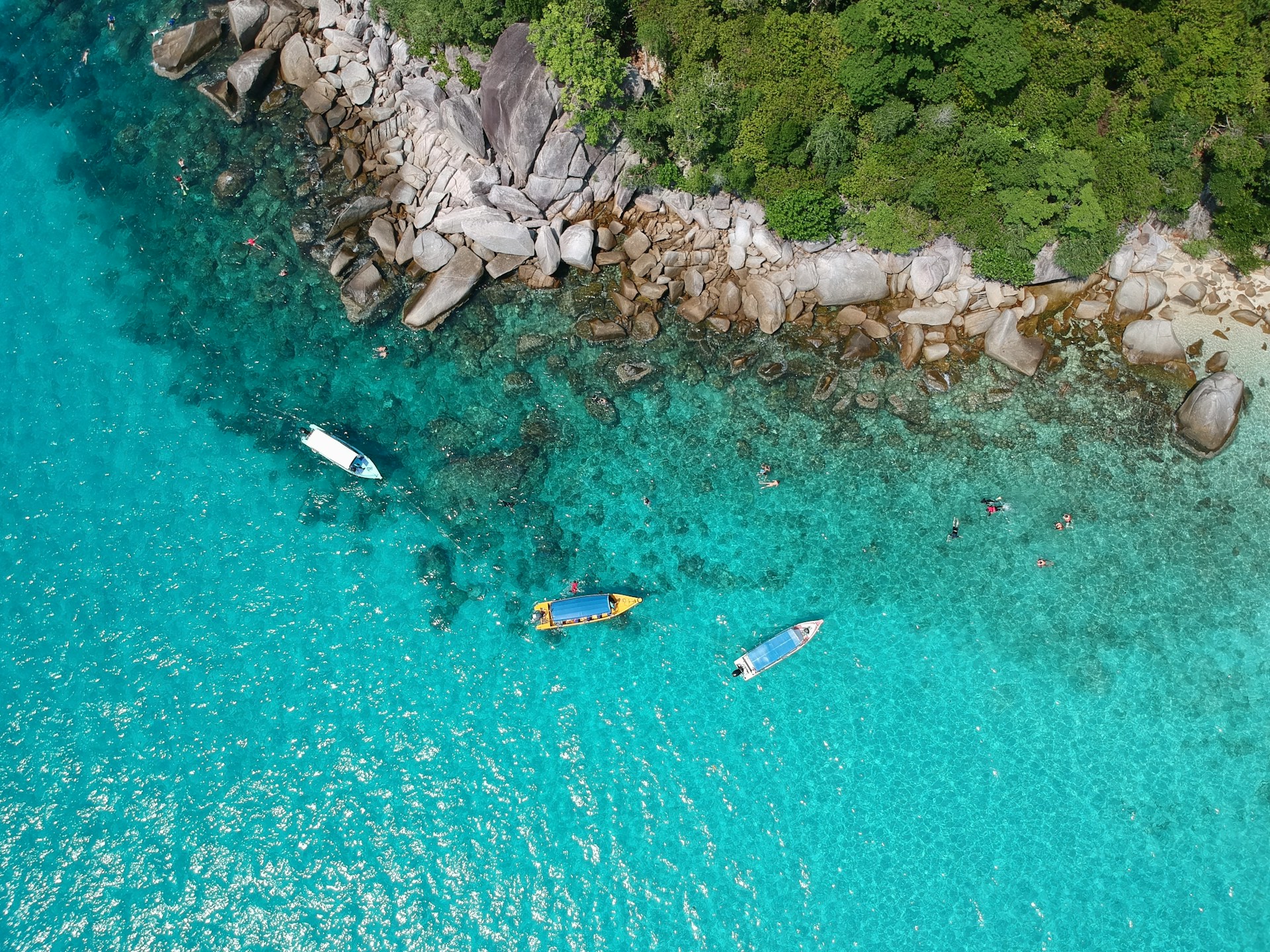 a top angle of perhentian islands in malaysia, showing a group of 3 boats in clear waters