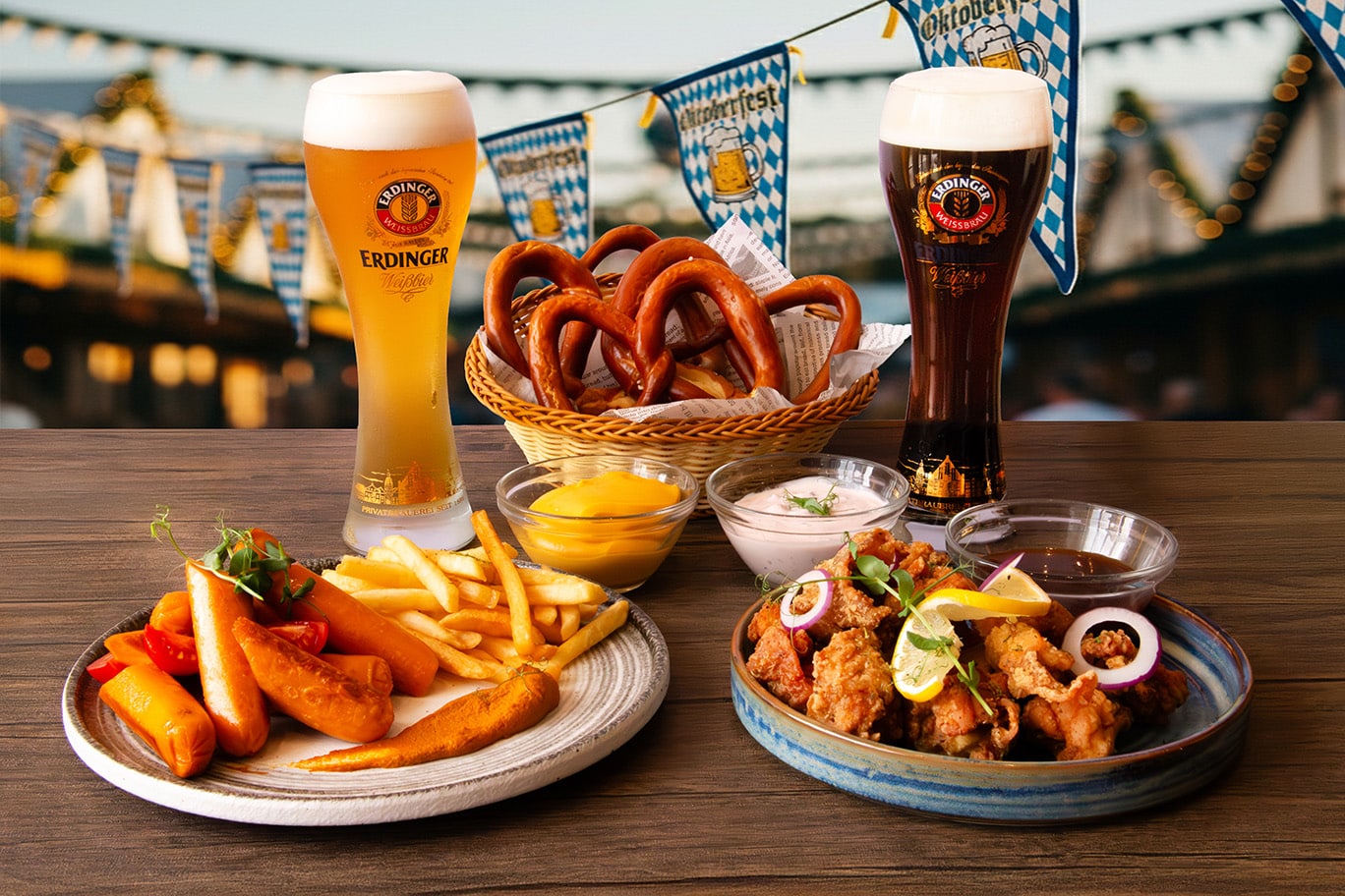 Holiday Inn Singapore Atrium Oktoberfest 2025 spread at Atrium Bar 317 featuring Erdinger Weissbier, Erdinger Dunkel, German pretzels, currywurst with fries, crispy chicken bites, and Bavarian dipping sauces.