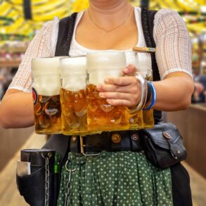 Oktoberfest, Munich. Waiter in traditional Bavarian costume serving beers, close up view. October fest German beer festival.