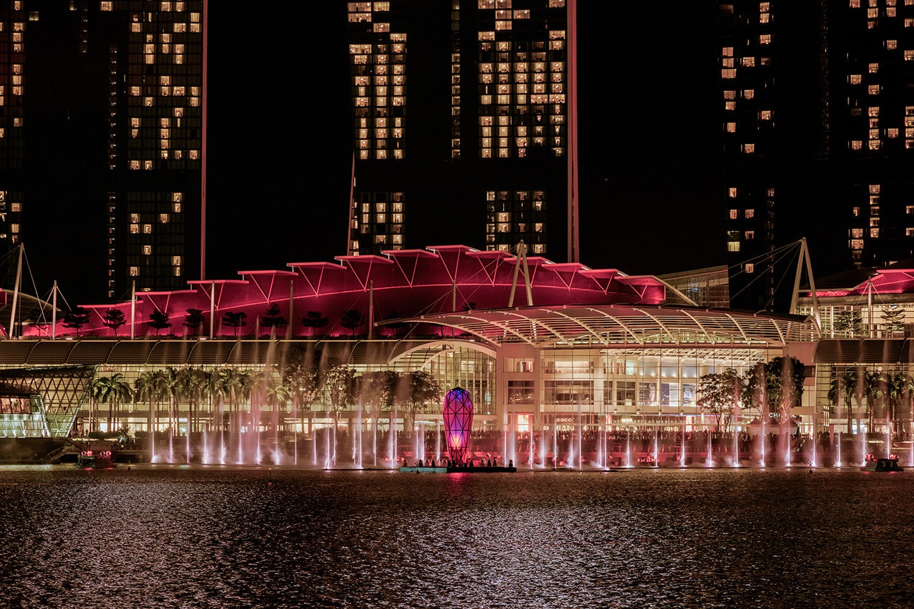 Night view of Marina Bay Sands waterfront illuminated in pink during the Spectra light and water show in Singapore.