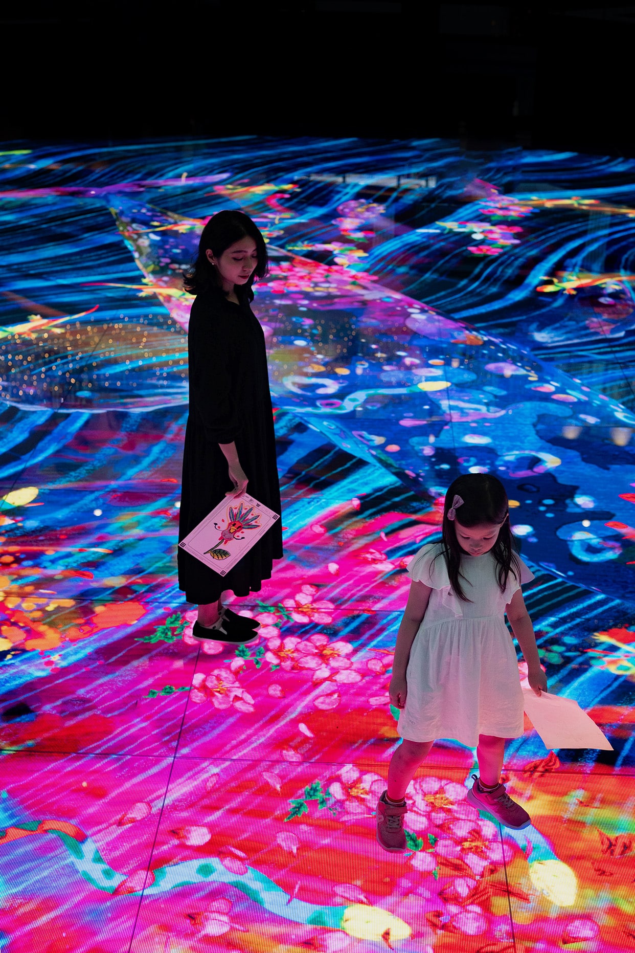 Children interacting with Digital Light Canvas by teamLab at Marina Bay Sands, surrounded by vivid digital koi and floral projections.