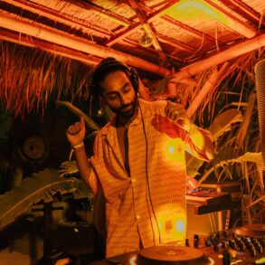 DJ HIMMAT performing in Bali under warm amber lights, immersed in tropical surroundings while spinning organic house and world electronic music.