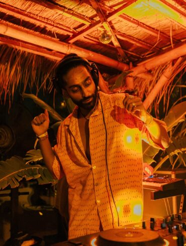 DJ HIMMAT performing in Bali under warm amber lights, immersed in tropical surroundings while spinning organic house and world electronic music.