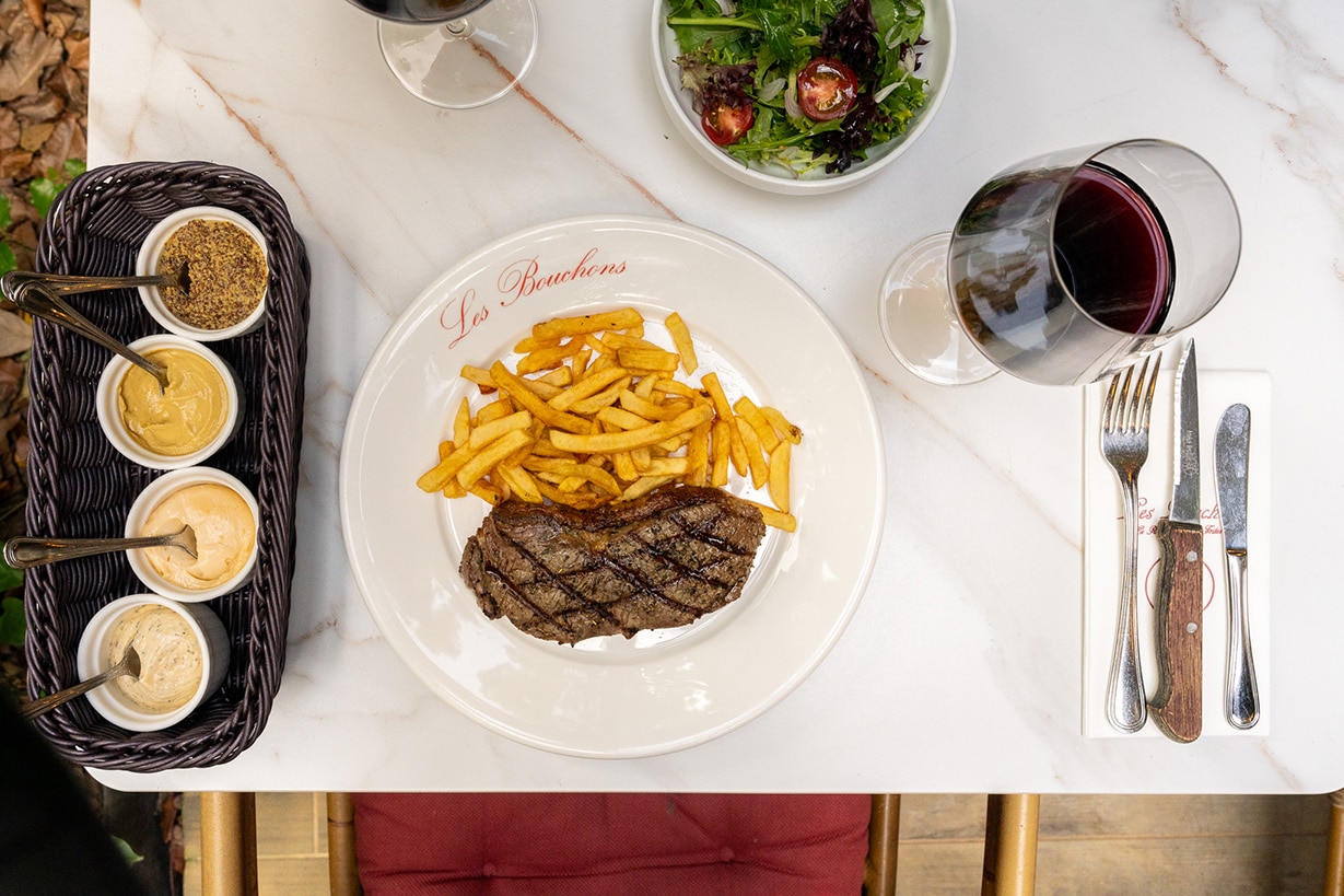 Classic steak-frites at Les Bouchons, Robertson Quay – grilled ribeye with golden fries, mustard condiments, and red wine.