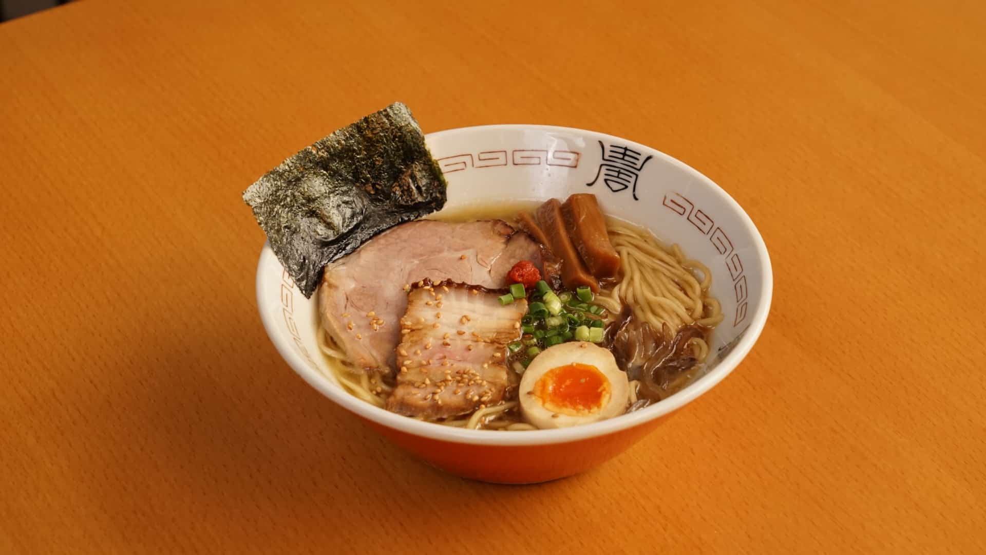 A steaming bowl of Shoyu Tonkotsu ramen served at Kenji’s Ramen Lab in 72 Courtyard Bangkok, featuring chashu pork, soft-boiled egg, seaweed, and noodles on a wooden table.
