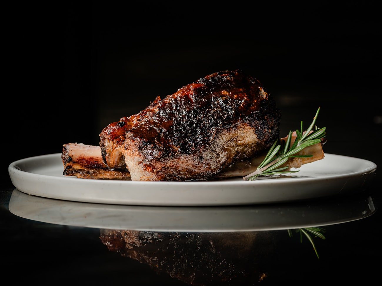 Charred short ribs grilled over live fire at WILD/FIRE, UE Square – wood-fired meat showcasing bold, flame-kissed flavours.