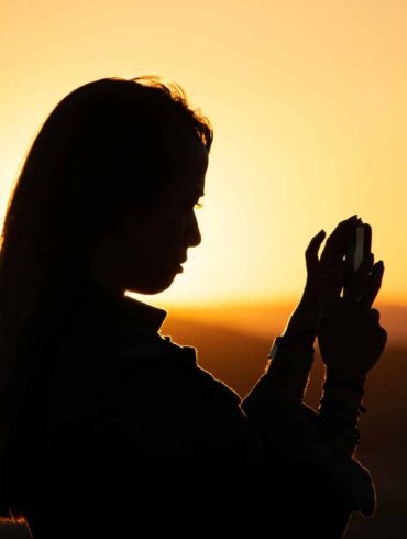 Silhouette of a female traveller using smartphone at sunset, representing eSIM connectivity for digital nomads and remote workers in 2025 travel