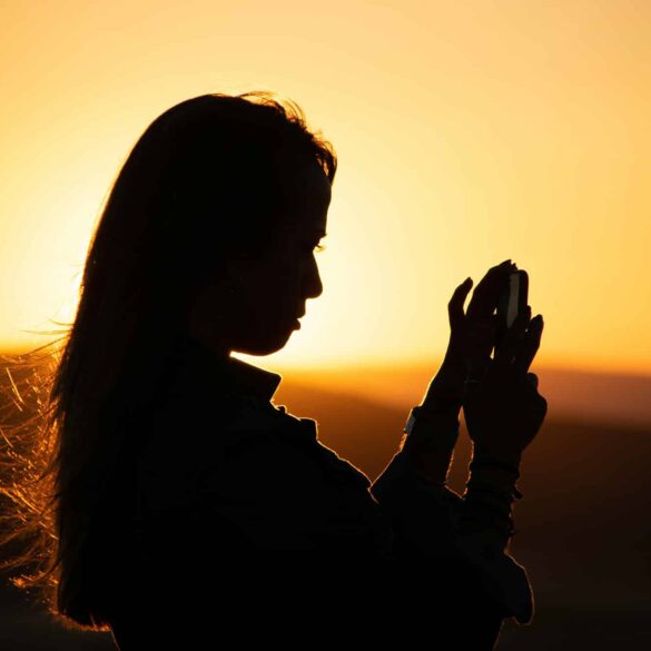 Silhouette of a female traveller using smartphone at sunset, representing eSIM connectivity for digital nomads and remote workers in 2025 travel