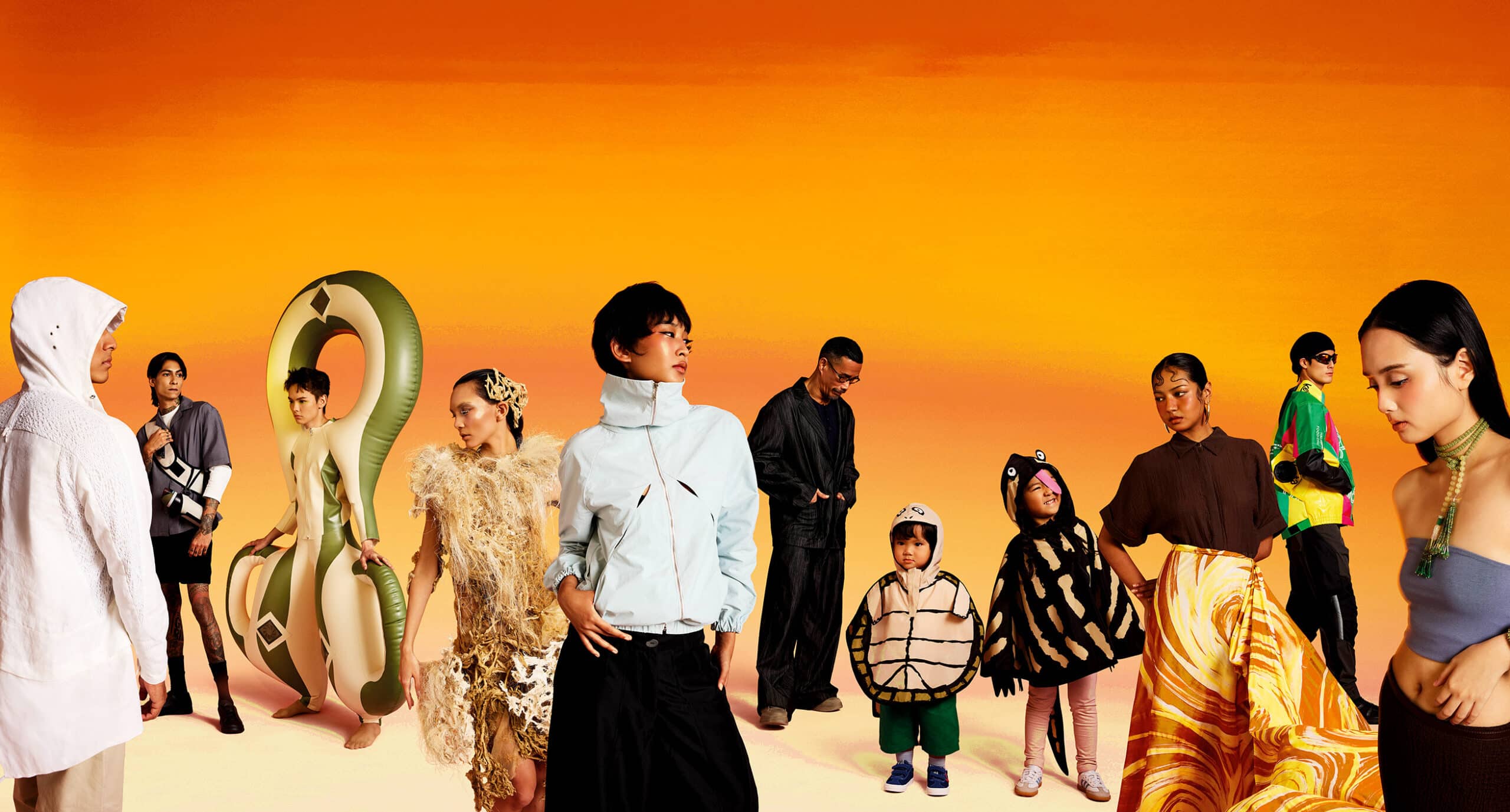 Full cast group photo from HOT BODIES Heatwear Exhibition in Singapore, featuring models wearing climate-responsive fashion designs against a vivid orange sunset backdrop.