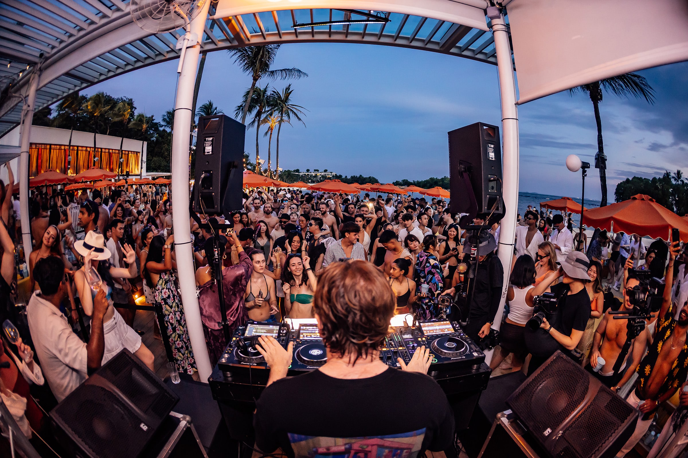 DJ-led beach party at Tanjong Beach Club during New Year’s Eve Singapore celebration with dancing crowd and sunset vibes