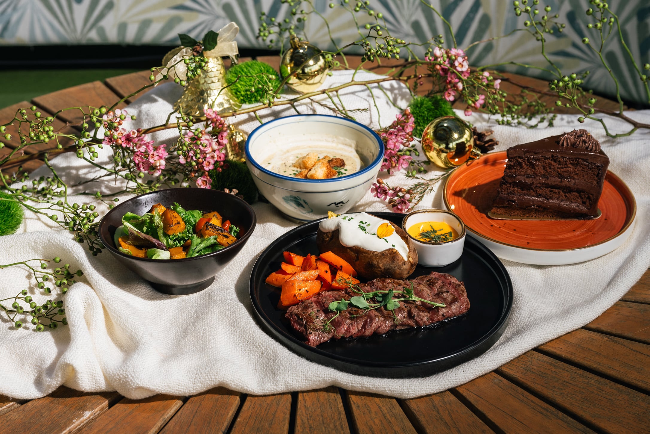 Christmas Eve 4-course festive dinner set at Wildseed Bar & Grill in Singapore, featuring grilled steak, soup, salad, and chocolate cake, styled with holiday decorations.