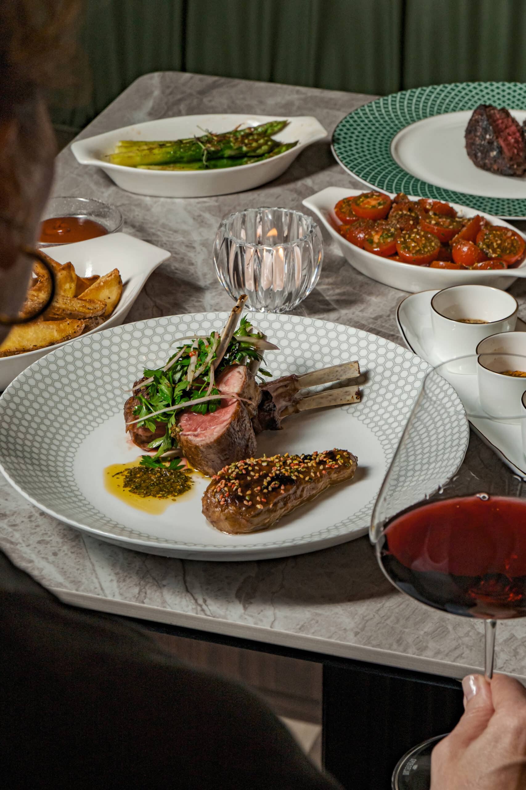 Luxurious dining at 54° Steakhouse Singapore, featuring lamb rack and modern sides, with elegant plating and red wine pairing.