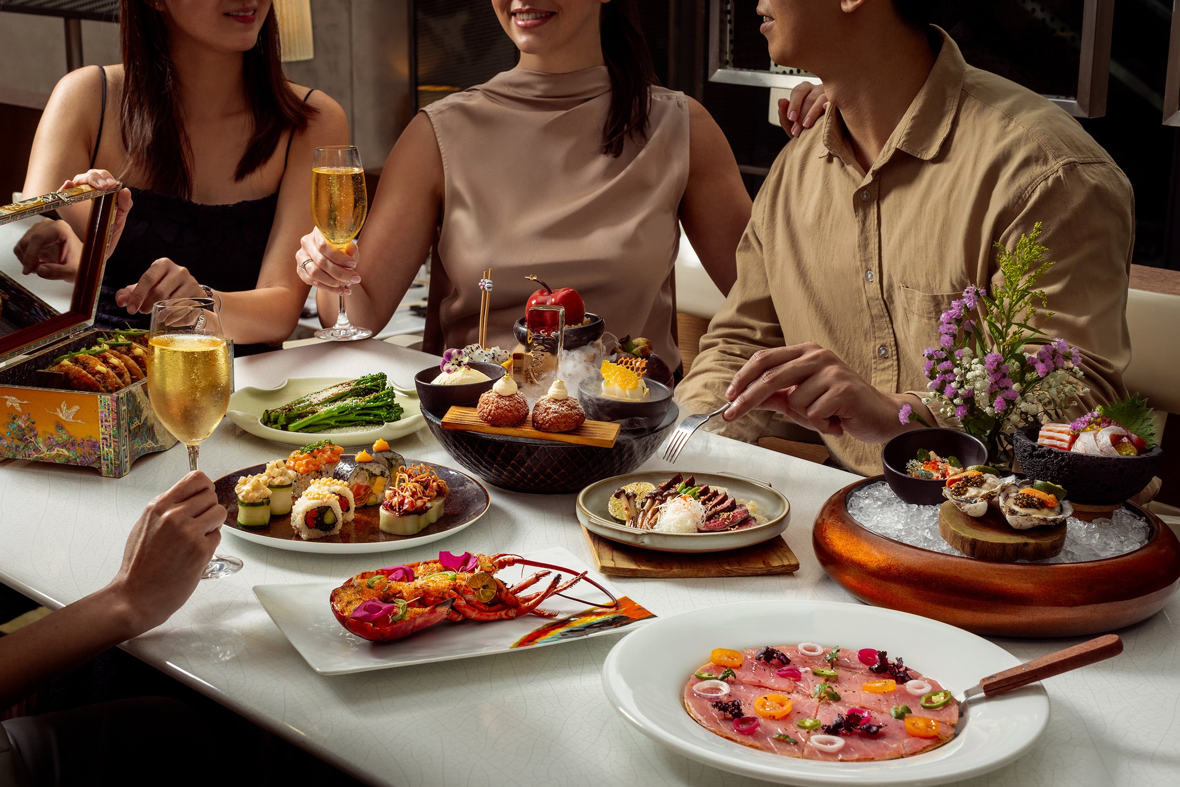 Guests toasting over a modern Japanese-Korean Christmas Day lunch at Akira Back, JW Marriott Singapore South Beach, surrounded by gourmet dishes and holiday cheer.