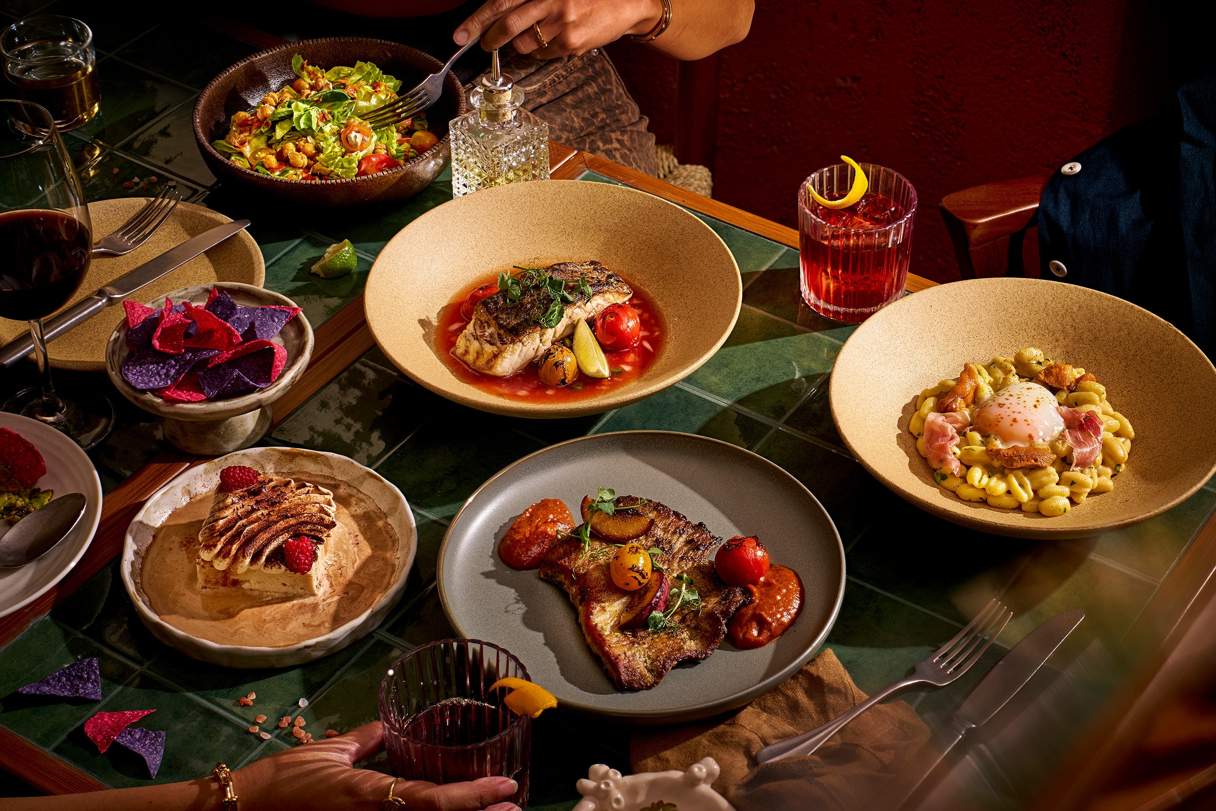 Vibrant dinner spread at MyX restaurant in Chip Bee Gardens, Singapore — featuring Latin- and Southern-inspired plates like fish stew, pasta, and grilled meats.