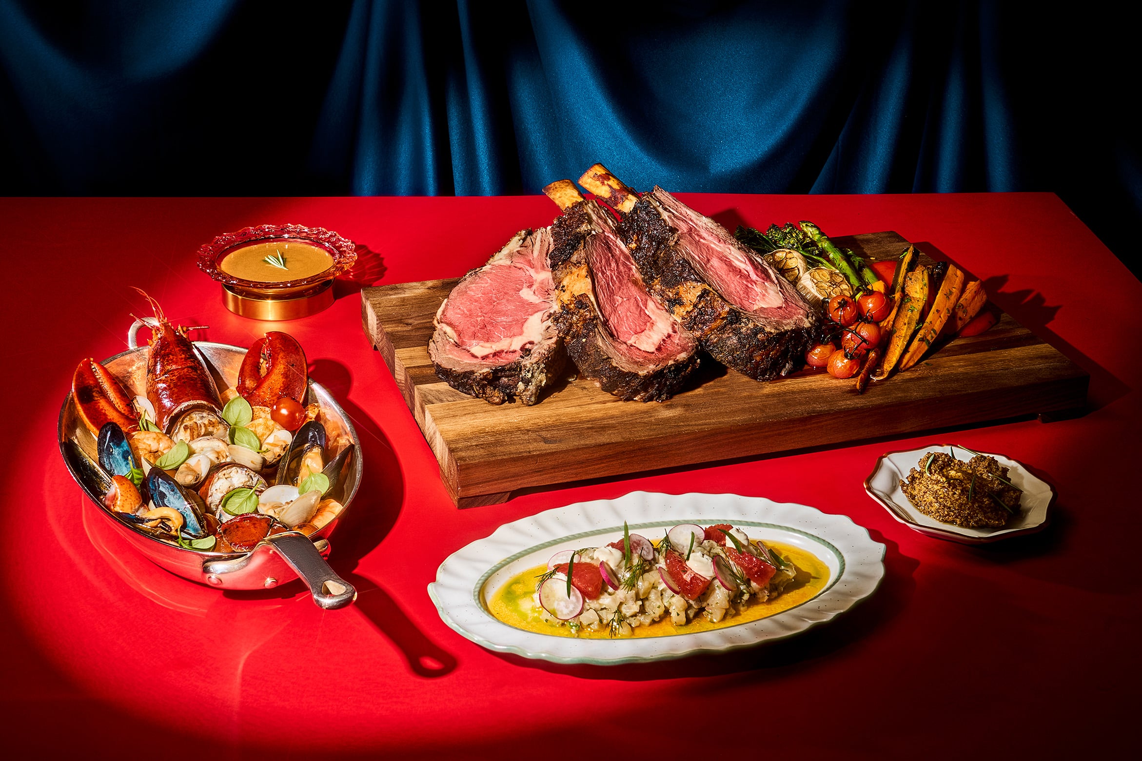 Grand Italian Buffet Christmas dish from Pete’s Place, Grand Hyatt Singapore, showcasing roast meats, grilled vegetables, and premium seafood on a red table setting.