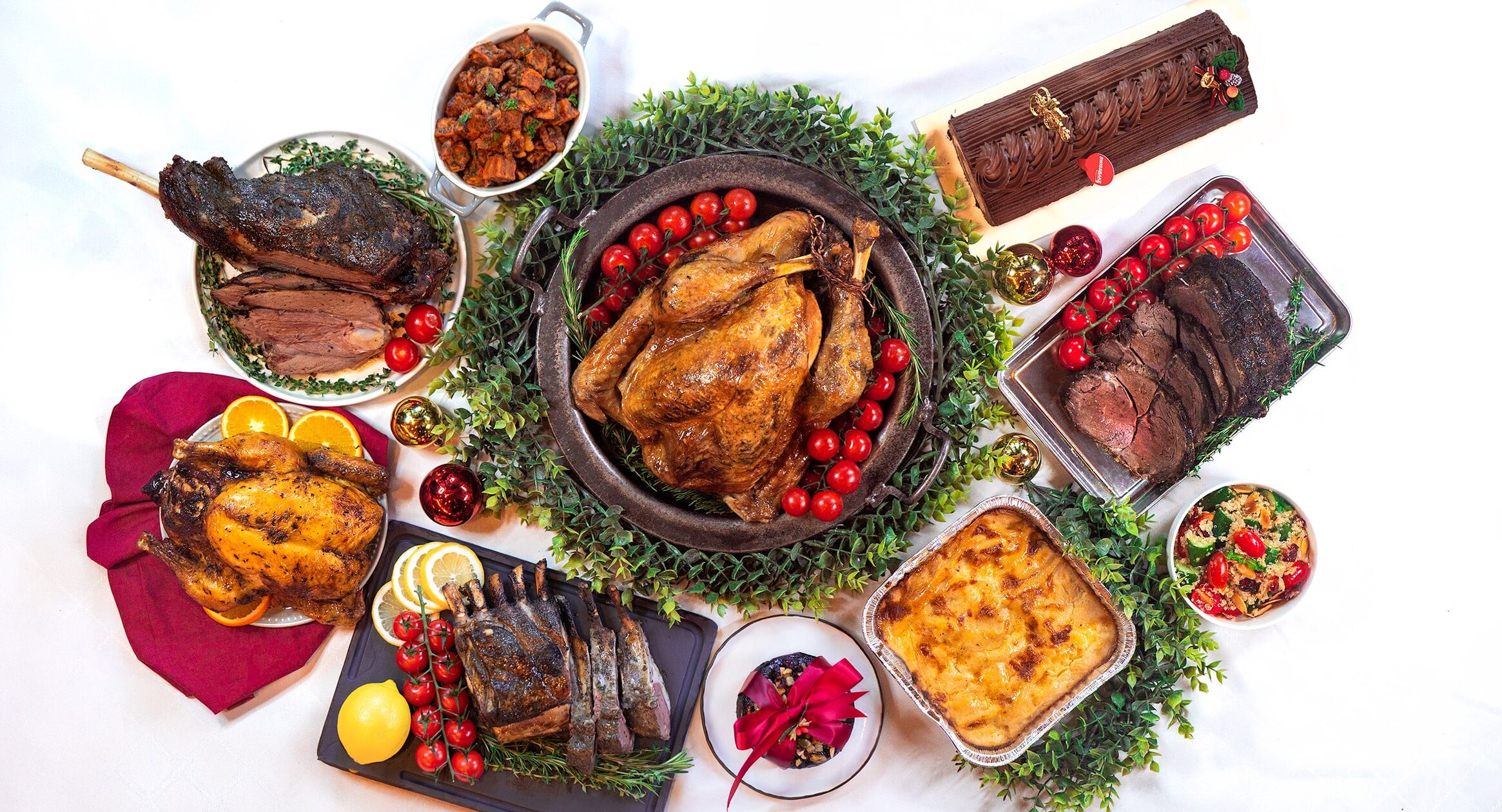Swissbake halal-certified Christmas takeaway spread featuring whole roast turkey, lamb leg, beef striploin, chocolate yule log cake, and baked macaroni.