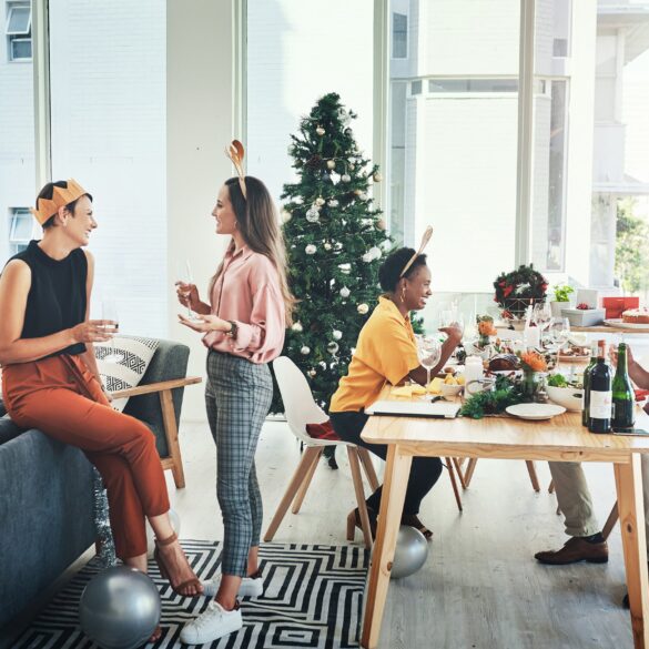 Festive office Christmas party with colleagues in holiday hats, enjoying catered food and drinks — showcasing in-office celebrations in corporate culture.
