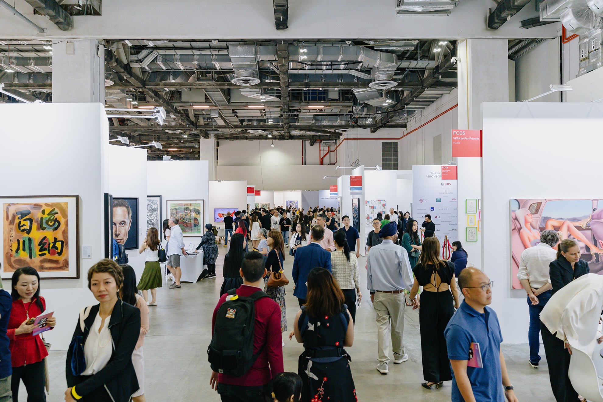 Visitors explore contemporary art booths at ART SG 2025 during Singapore Art Week, showcasing international and regional galleries in a vibrant indoor fair setting.