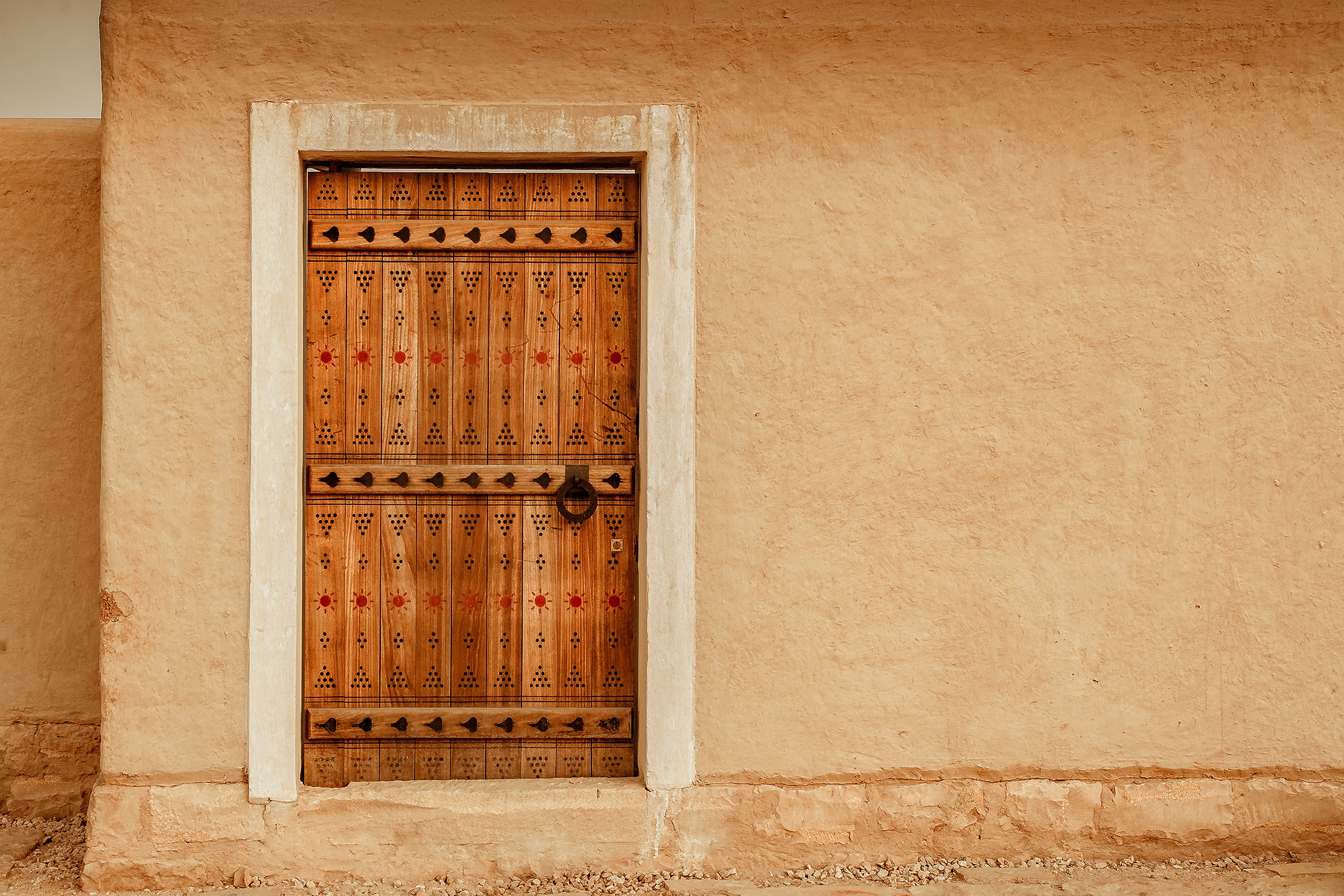 Traditional Najdi wooden door with geometric carvings in the heritage mudbrick architecture of Diriyah, Saudi Arabia.