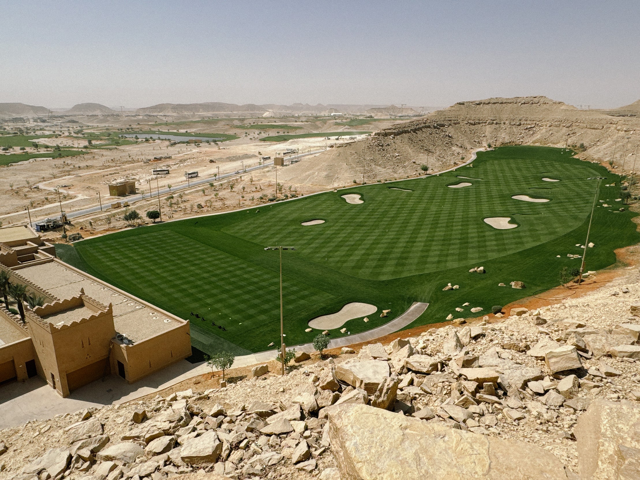 Panoramic view of Wadi Safar’s Greg Norman–designed golf course in Diriyah, Saudi Arabia, set against desert cliffs and emerging luxury developments.