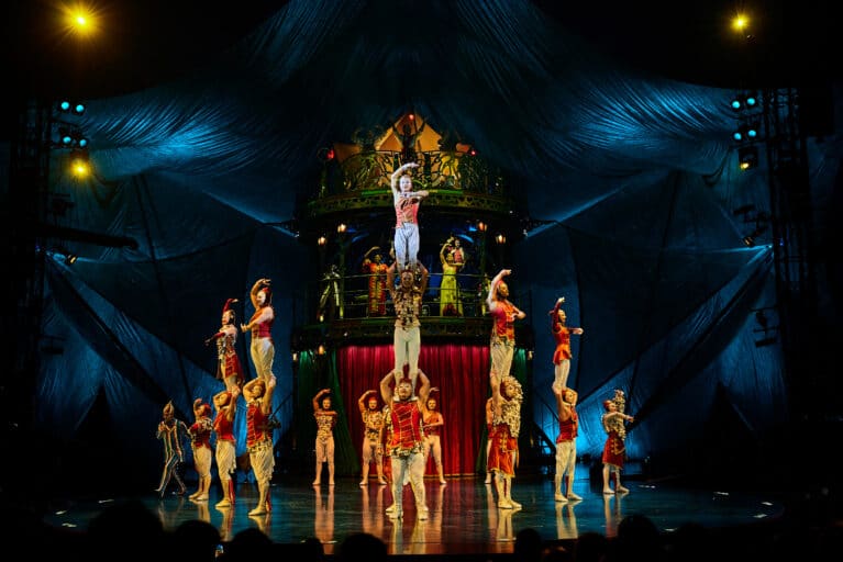 Cirque du Soleil KOOZA ensemble cast performing a vibrant circus scene on stage, blending acrobatics, theatre, and live music in Singapore.