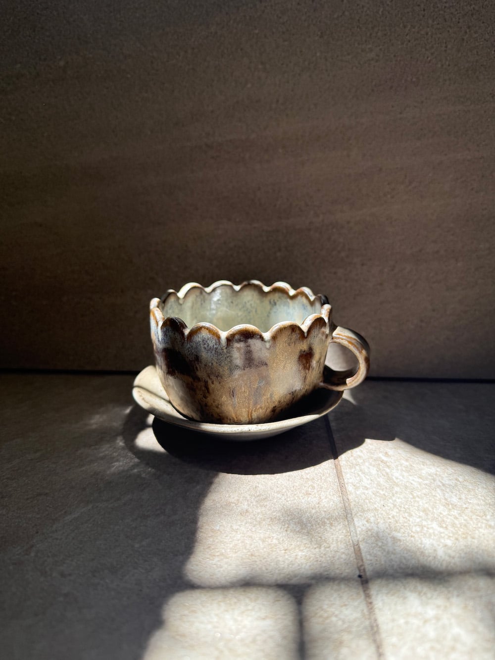 Handcrafted scallop-edge teacup and saucer by Kapuuut, a one-of-a-kind ceramic gift made in Singapore.