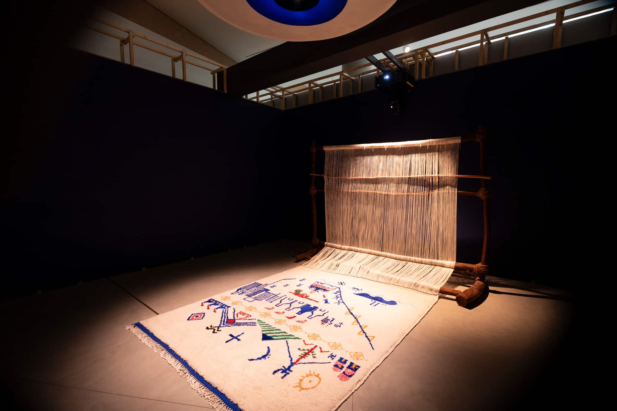 Tiɣrist – Threads of Exile” by Samia Dzaïr at Diriyah Art Futures in Saudi Arabia, featuring a woven textile installation under dramatic lighting.