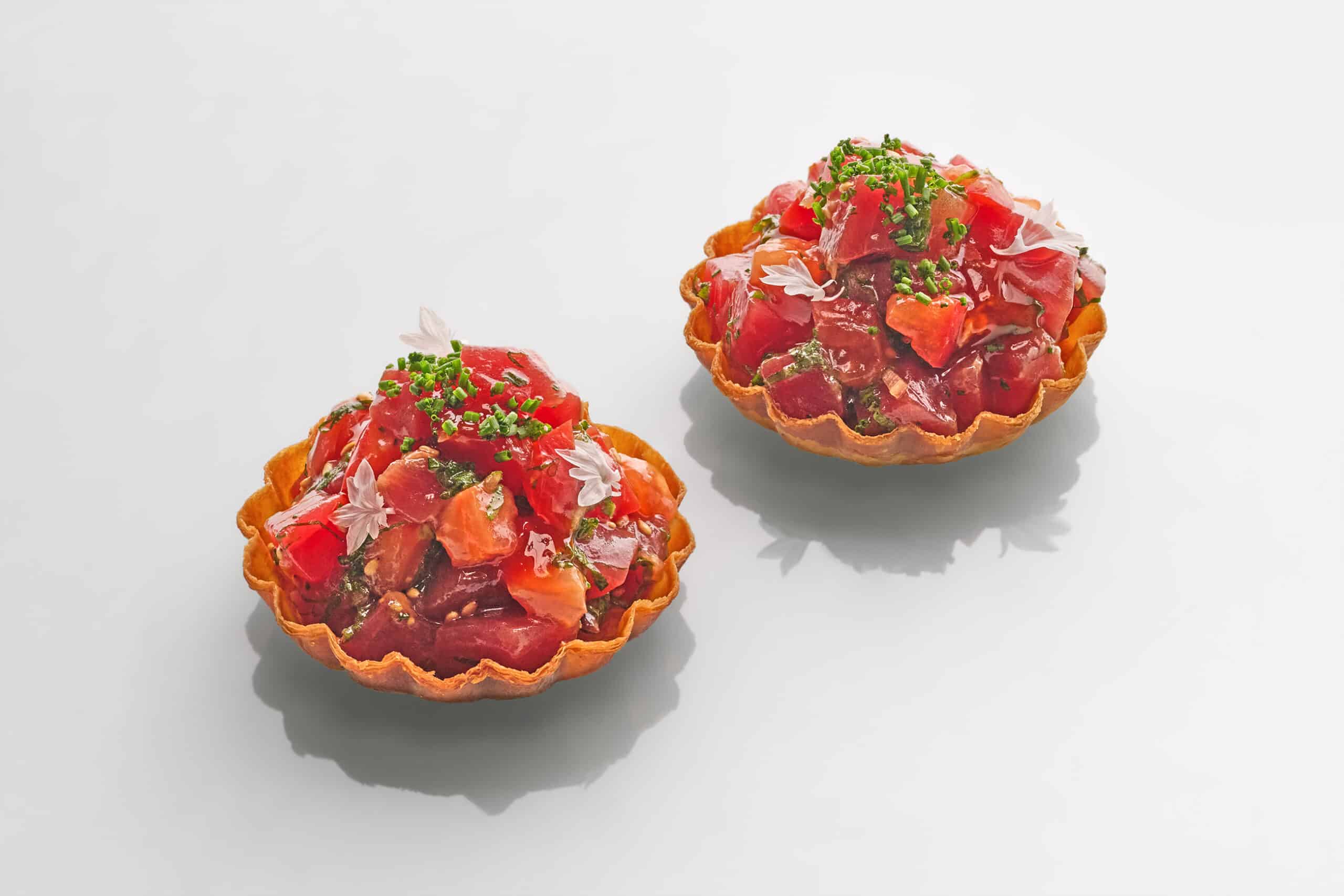 Tuna tartlette at AMI Patisserie featuring bluefin tuna tartare with oba leaf and myoga on a honey-brushed filo pastry base, garnished with microgreens and edible flowers