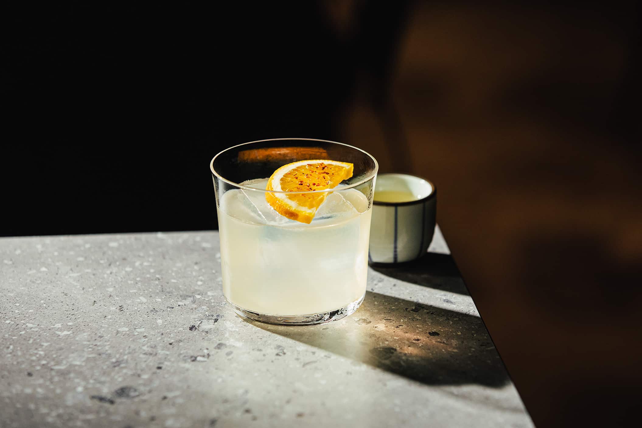 Cat Bite Margarita cocktail in a rocks glass with a dehydrated citrus wheel garnish and small side pour of neat tequila at Cat Bite Club Singapore