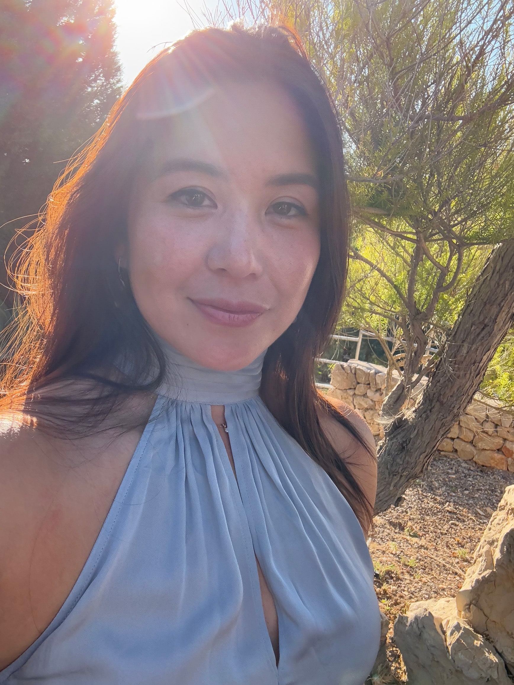 Portrait of Sarah Yvonne Wong, co-founder of FORNA, wearing a light blue halter dress, photographed outdoors with soft sunlight — the face behind the intimacy jewellery brand.