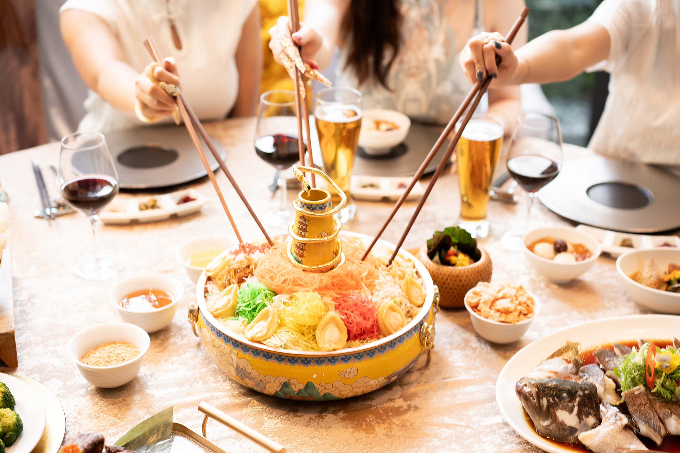 Guests tossing a colourful prosperity fruit yu sheng at Mercure Singapore, featuring fresh fruits, vegetables, and festive sauces for Lunar New Year