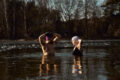 Man and woman practising ice bath cold water immersion together in a frozen lake, highlighting the mental and physical benefits of cold exposure in nature.