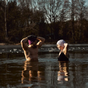 Man and woman practising ice bath cold water immersion together in a frozen lake, highlighting the mental and physical benefits of cold exposure in nature.