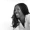 Profile photo of African woman with long hair wearing a white blouse.