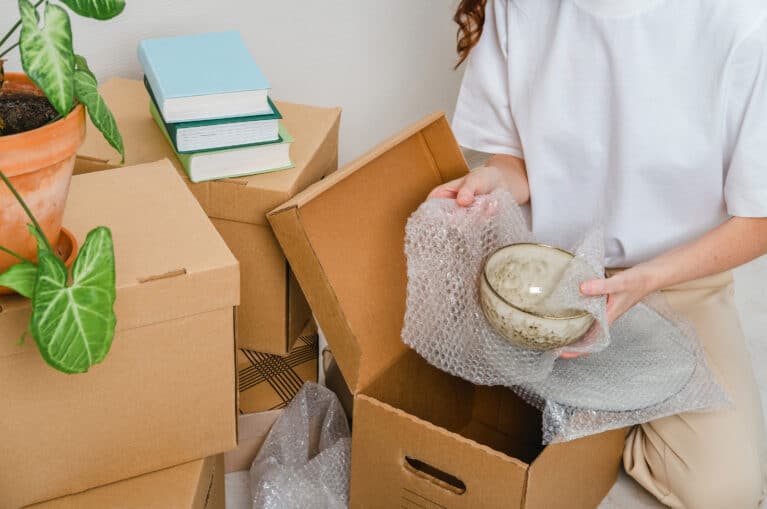 Woman packing belongings in cardboard boxes for moving abroad