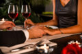 Couple holding hands over candlelit dinner table with red wine for Valentine’s Day celebration in Singapore 2026.
