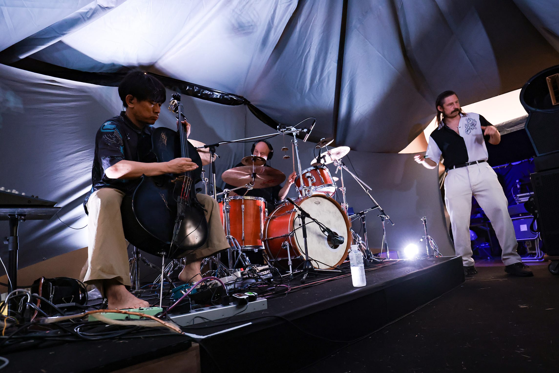 Experimental live band performance at rural techno festival in Japan, blending acoustic and electronic sounds on an intimate stage setting