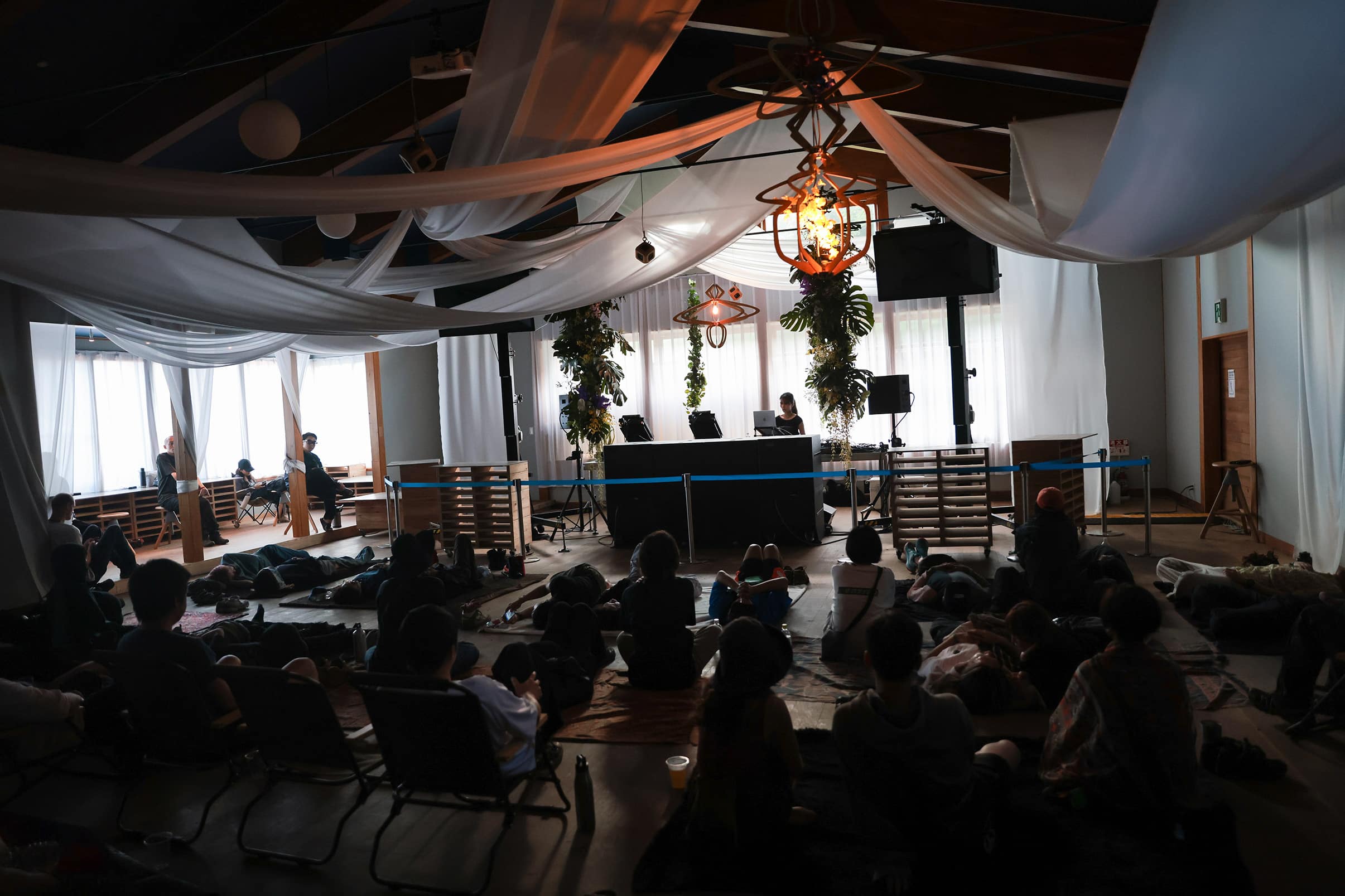 Ambient listening room at rural 2025, with laid-back crowd enjoying a meditative DJ set indoors under flowing drapes and soft daylight