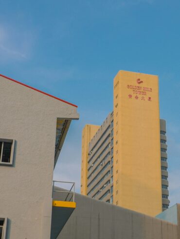 Golden Mile Tower in Singapore against a blue sky, with its distinctive yellow façade and signage visible from street level.