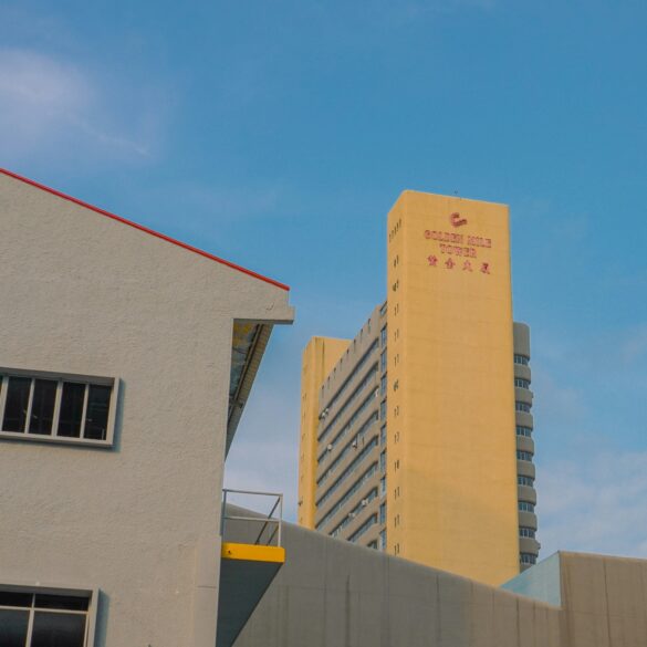 Golden Mile Tower in Singapore against a blue sky, with its distinctive yellow façade and signage visible from street level.