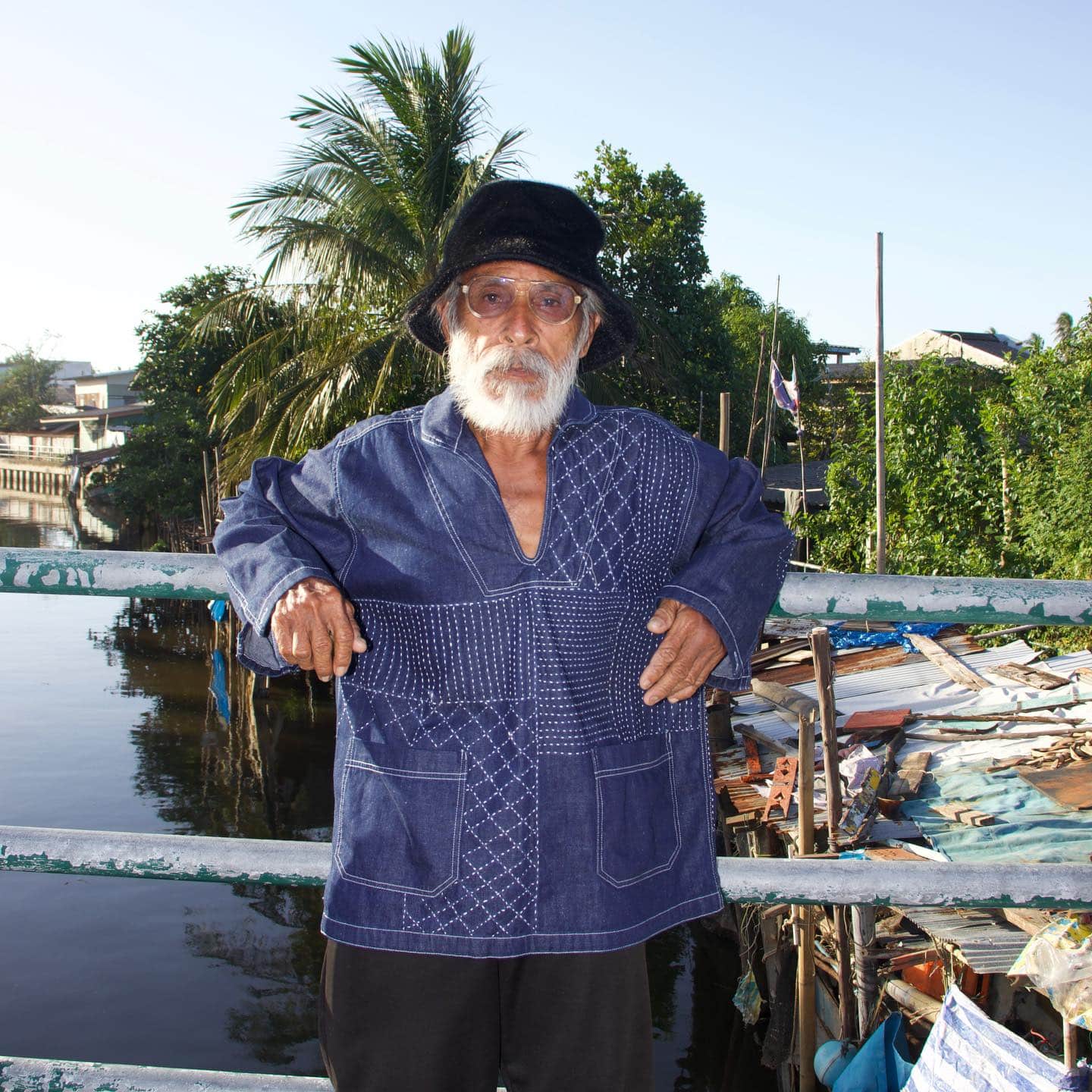 Designer wearing an indigo upcycled patchwork garment by Concur Patchwork in Thailand, highlighting sustainable fashion craftsmanship.