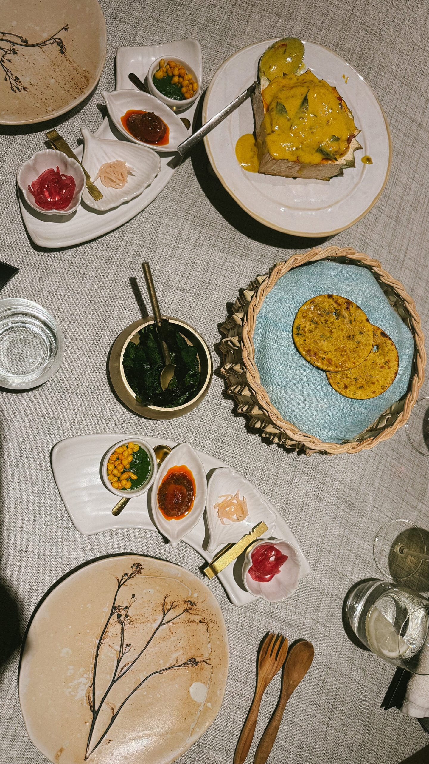 The “Tandoori Story” course at Gaa Bangkok featuring bread, pickles, and condiments served alongside a rich curry.