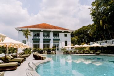Madison House Singapore pool with heritage colonial building backdrop and poolside cabanas at Fort Canning