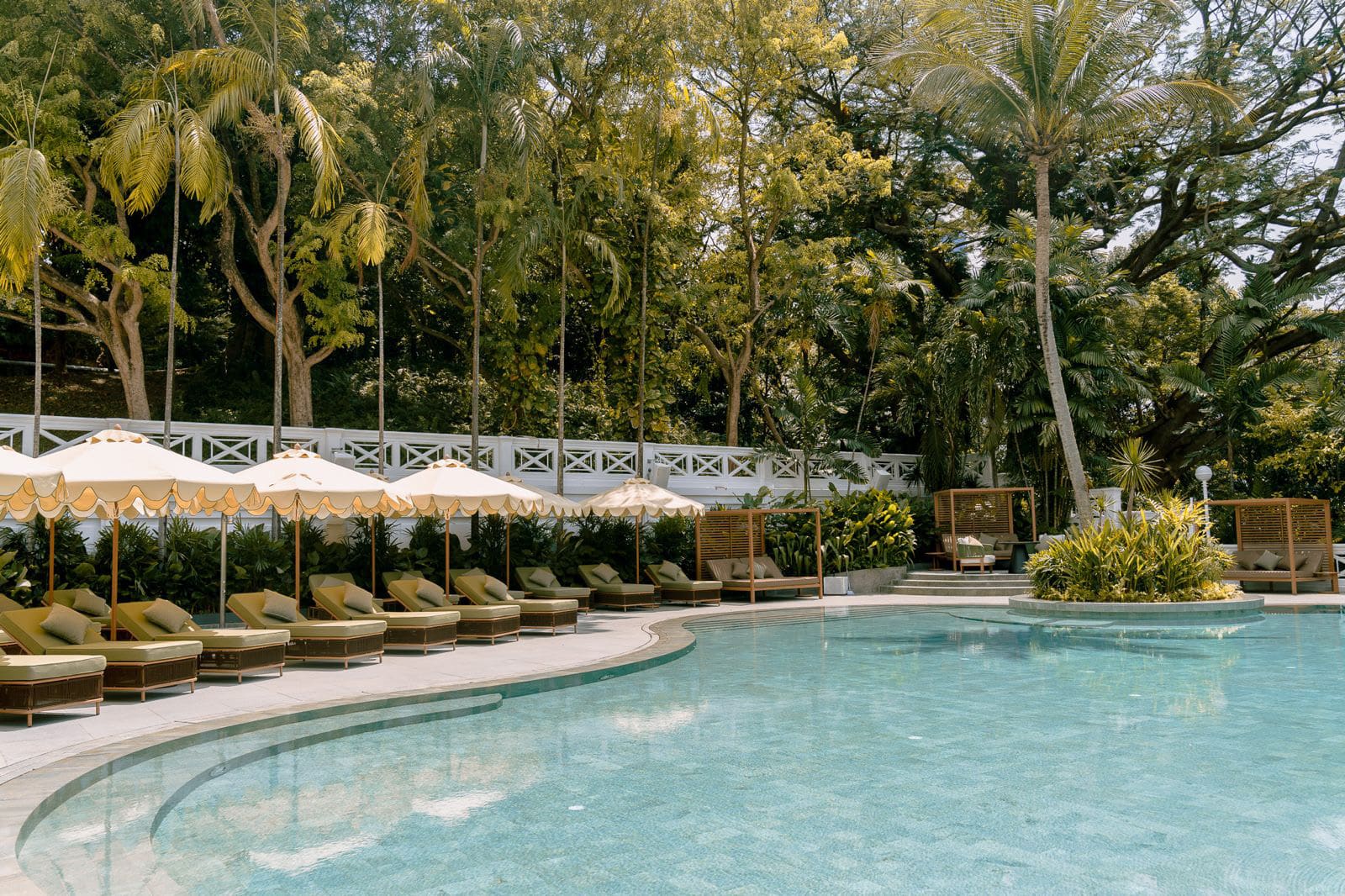 Madison House Singapore outdoor pool surrounded by tropical greenery and sun loungers at Fort Canning