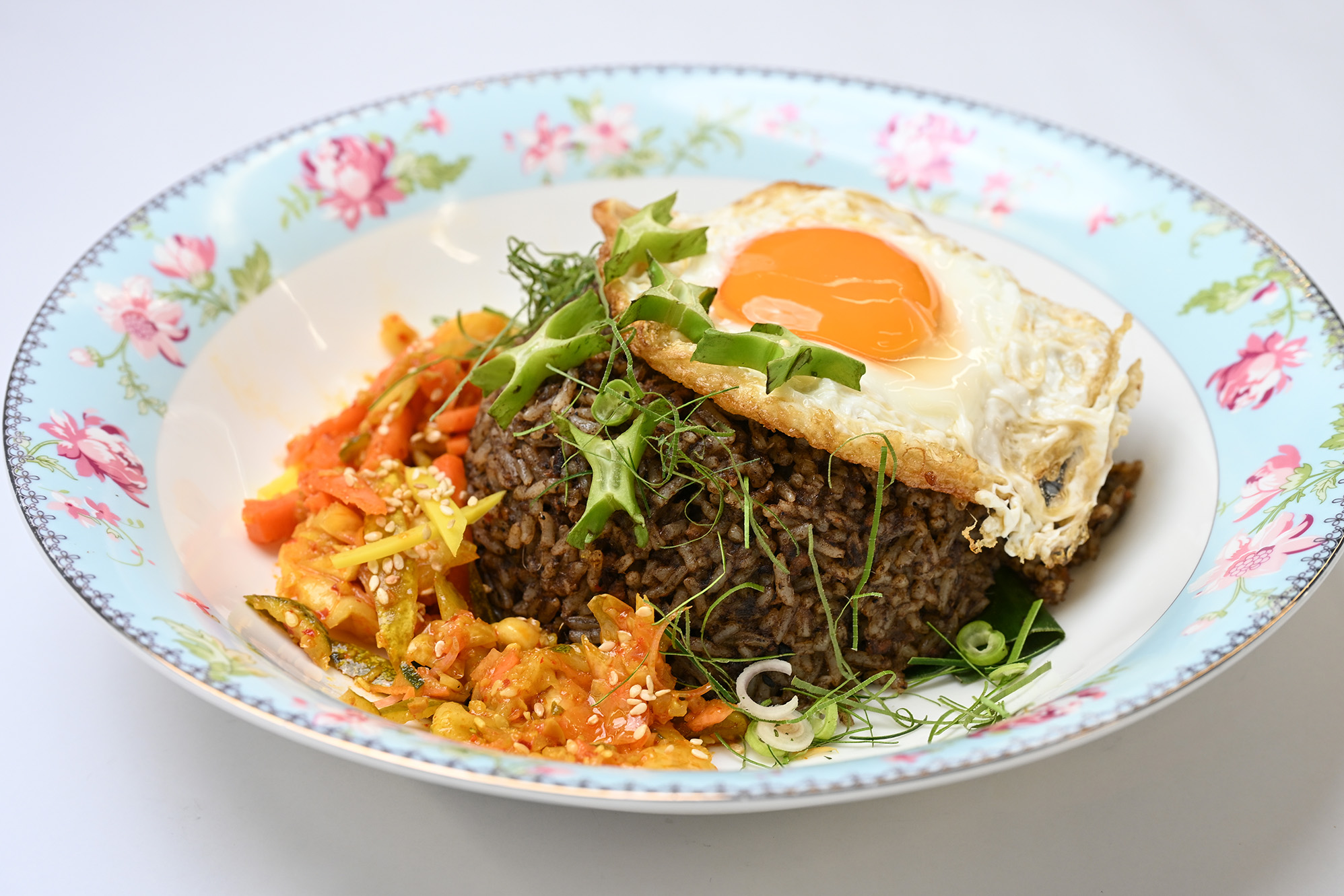 Buah keluak fried rice topped with a fried egg and sambal at The Peranakan Club Singapore