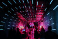 Crowd dancing under neon pink and blue lights inside an underground electronic music club in Moscow, Russia.