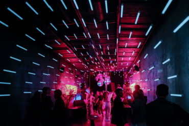 Crowd dancing under neon pink and blue lights inside an underground electronic music club in Moscow, Russia.