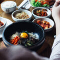 Korean bibimbap with egg yolk and assorted banchan on a dining table in Singapore